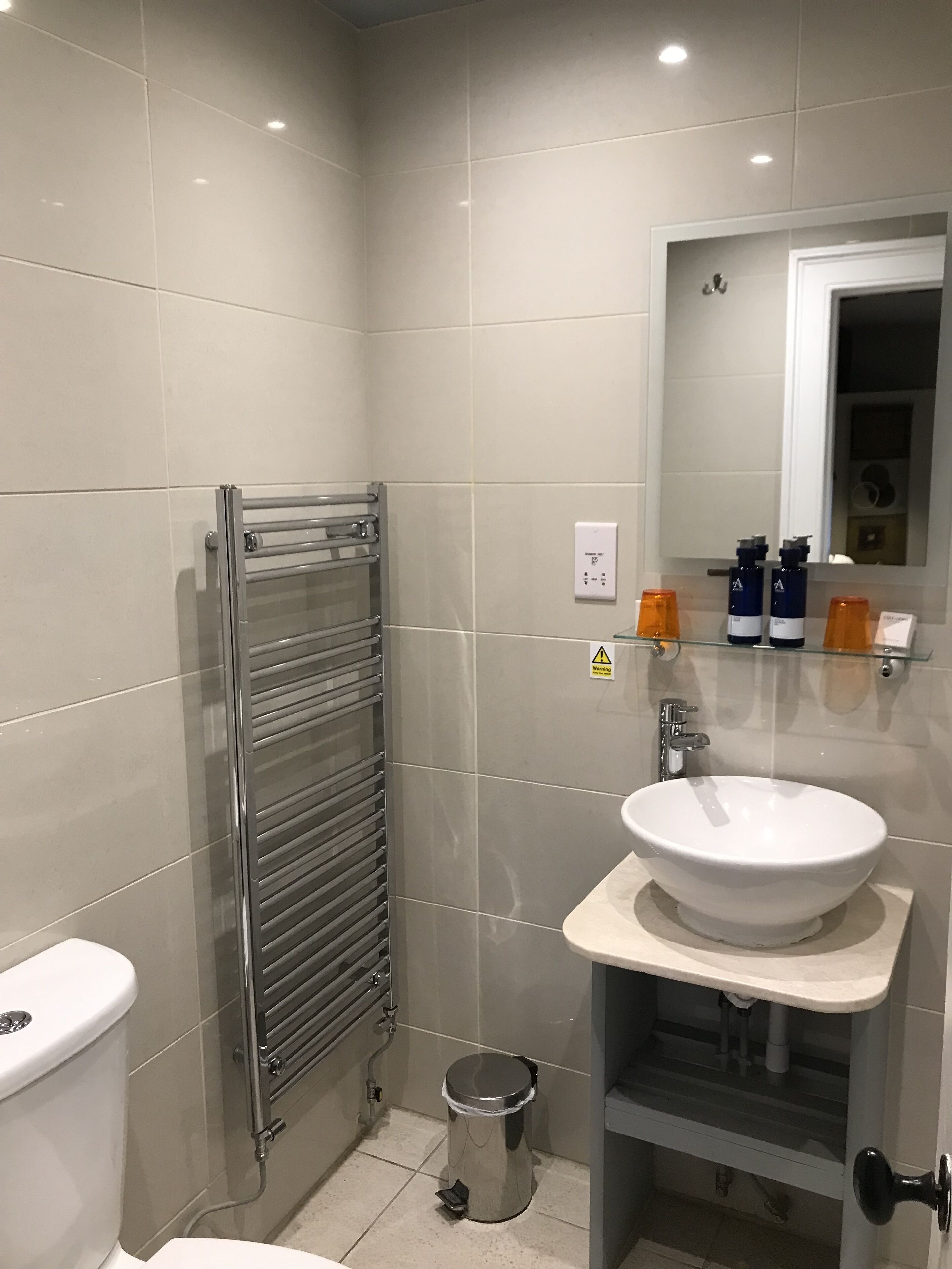A modern bathroom with a toilet, a sink, a mirror, and a towel rack.