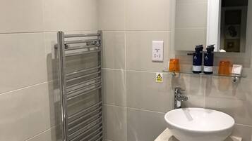 A modern bathroom with a toilet, a sink, a mirror, and a towel rack.