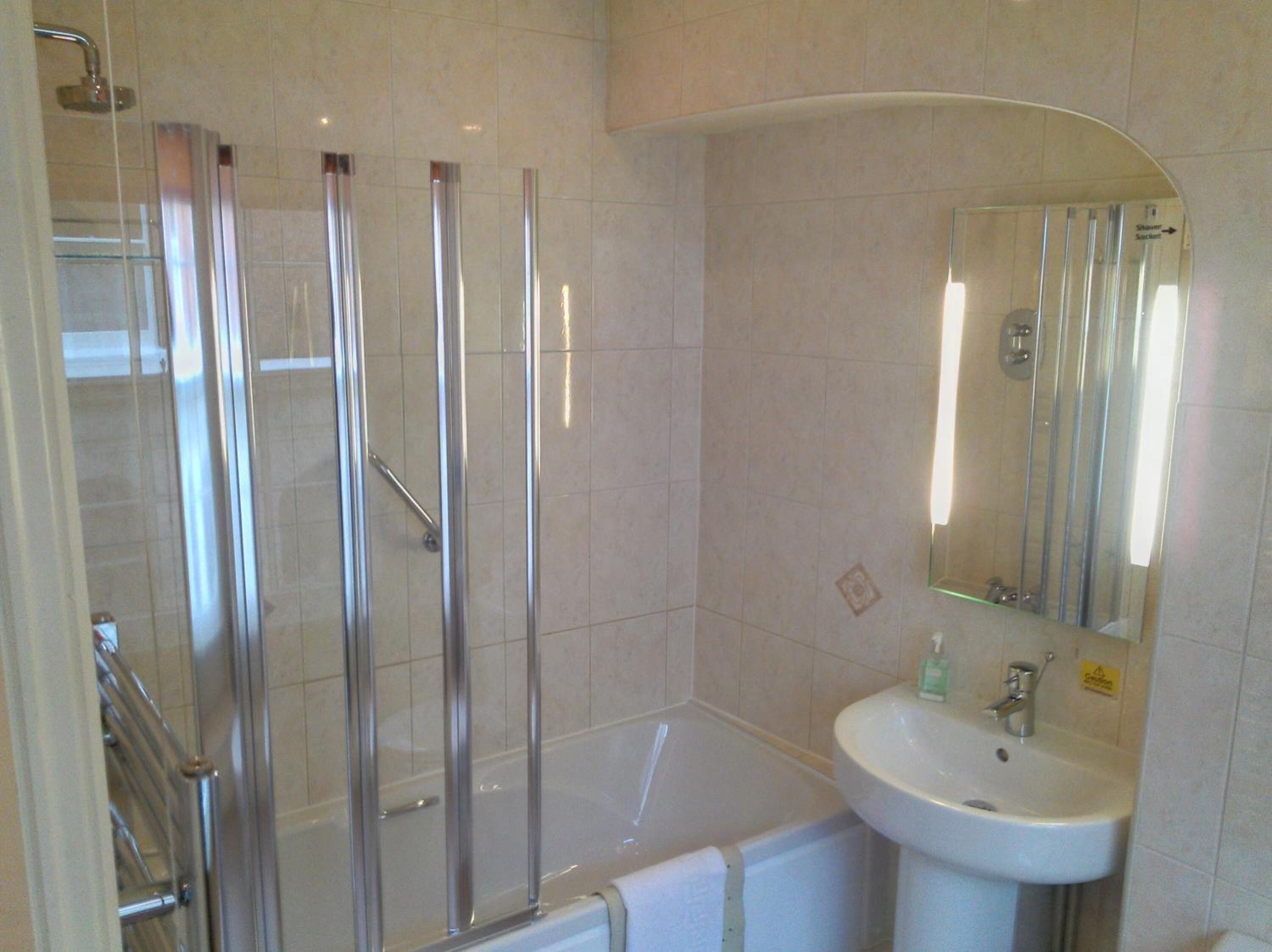 A bathroom with a glass-enclosed shower, a bathtub, and a sink with a mirror.