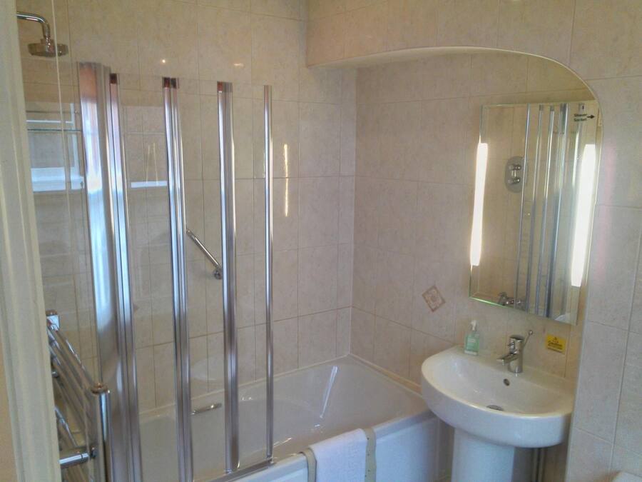 Une salle de bain dotée d’une douche à parois de verre, d’une baignoire et d’un lavabo avec un miroir.