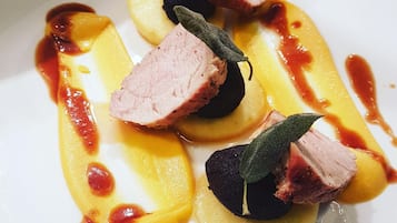 Um prato de comida com fatias de carne, um objeto redondo escuro e molho amarelo.