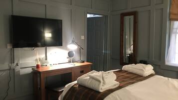 Un dormitorio con cama, escritorio, televisor, espejo y puerta.