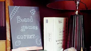 Una mesa de madera con juegos de mesa, una lámpara y un mapa enmarcado.