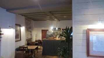 A cozy restaurant with wooden tables and chairs, a bar area, and a potted plant.