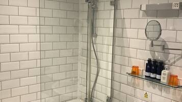 Un baño moderno con ducha de vidrio, una bañera blanca y un lavamanos con espejo.