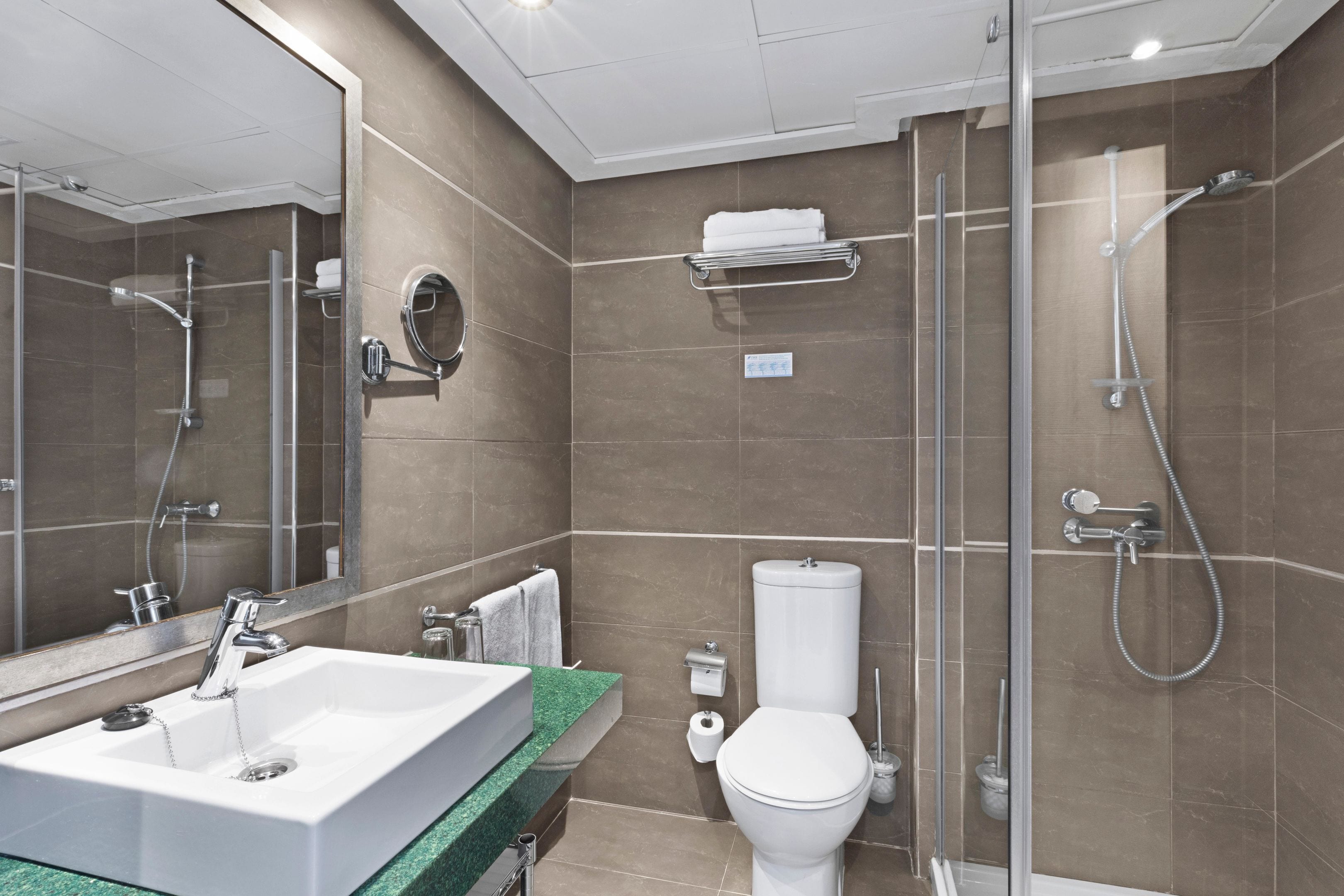 Ein modernes Badezimmer mit großem Waschbecken, Toilette und Duschbereich.