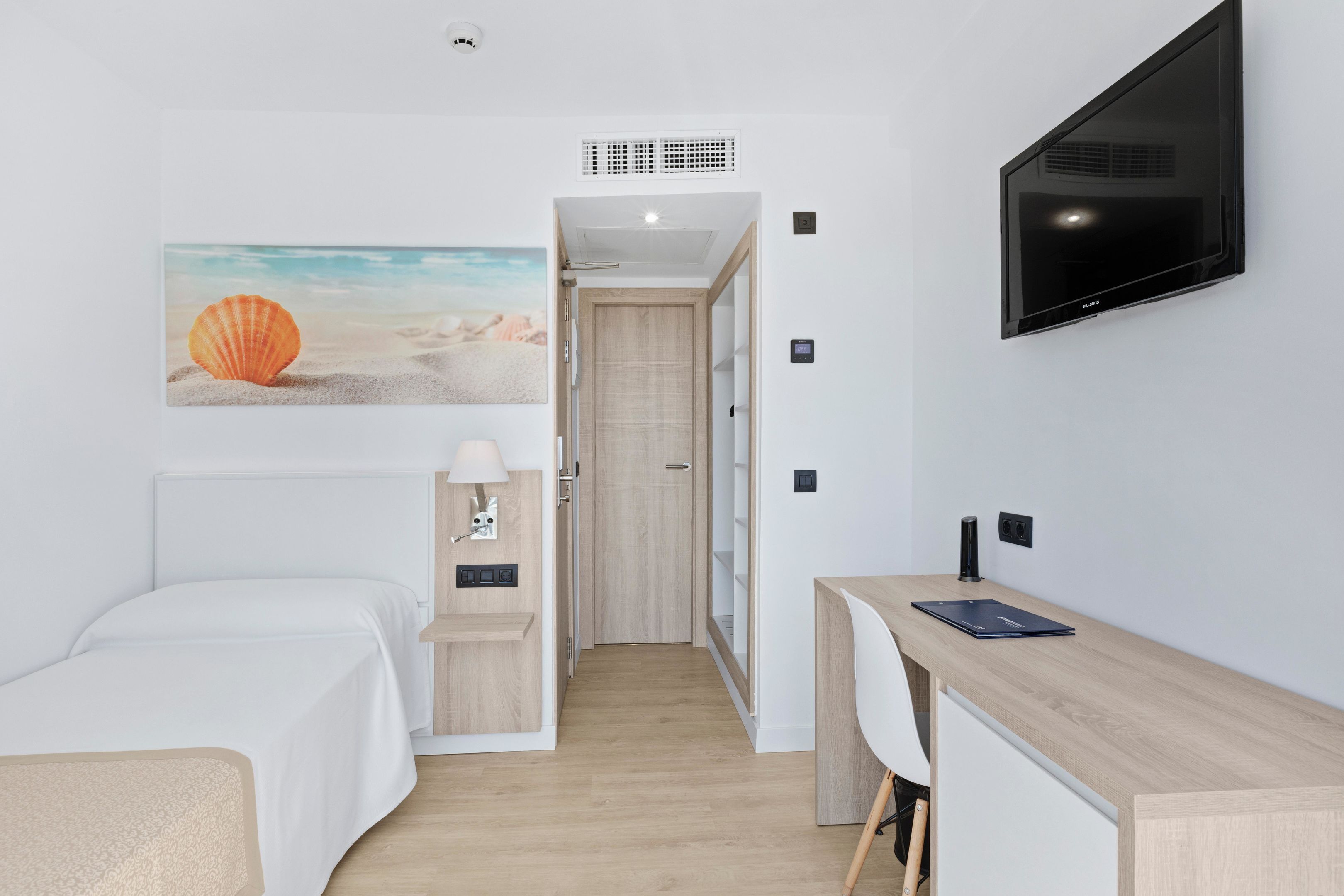 Une chambre d’hôtel moderne équipée d’un lit, d’un bureau et d’une télévision.