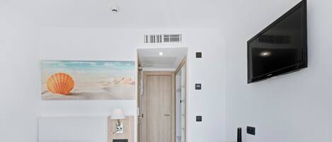Ein modernes Hotelzimmer mit Bett, Schreibtisch und Fernseher.