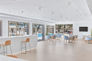 Un espacio interior amplio con grandes ventanales, vista a la piscina y muebles modernos.