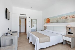Una habitación de hotel con una cama grande, mesitas de noche, un escritorio y un televisor.