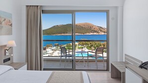 Ein Hotelzimmer mit Bett, Schreibtisch, Stuhl und Blick auf Pool und Strand.