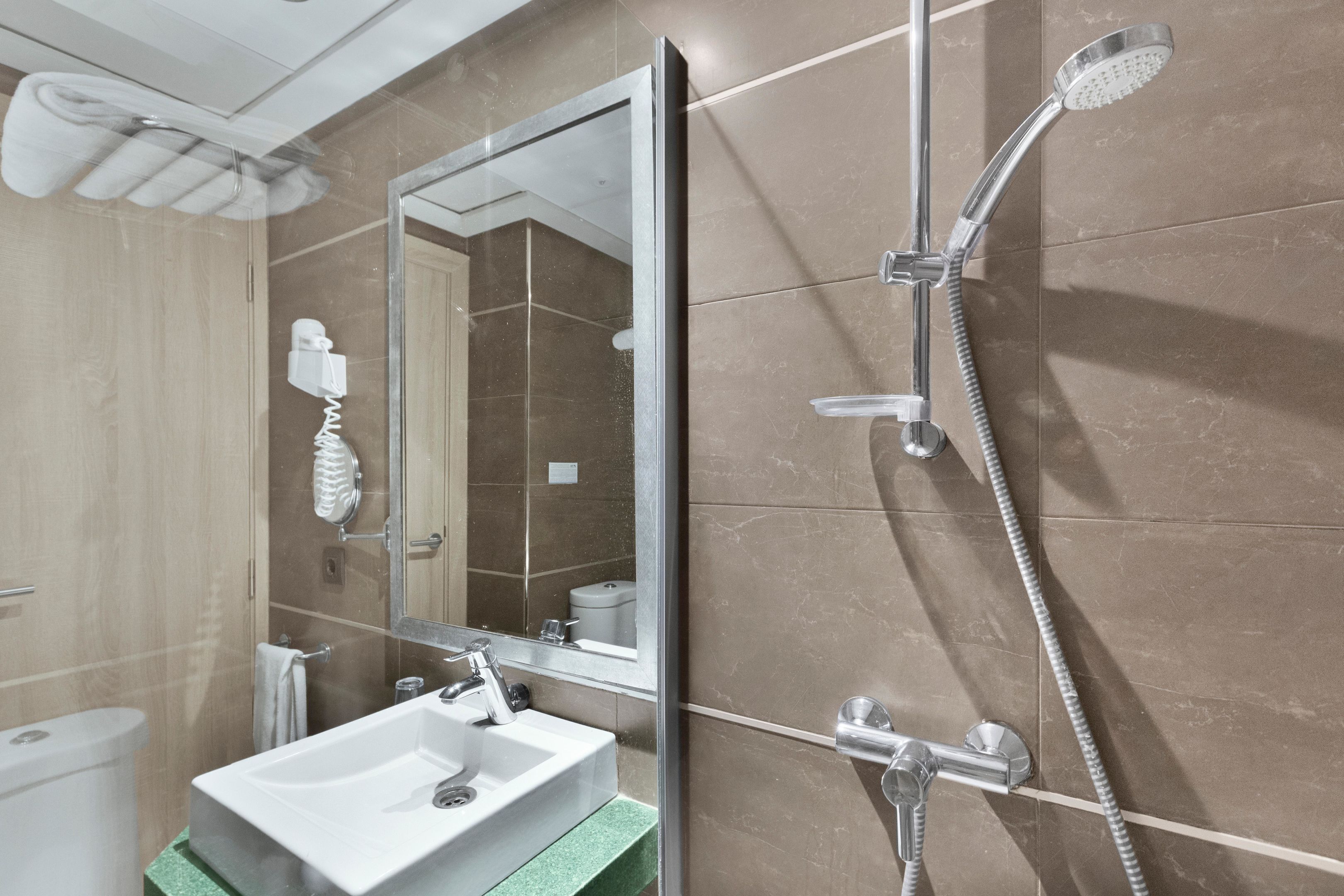 Un baño con ducha, lavabo y espejo.