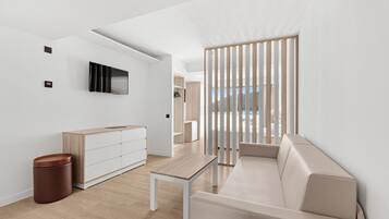 A modern living room with a sofa, a coffee table, a TV mounted on the wall, and a wooden partition.