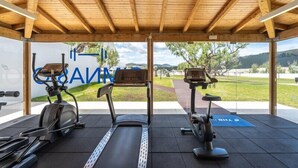 Un gimnasio al aire libre con equipo de ejercicio, una vista despejada del paisaje circundante y una estructura de madera en lo alto.