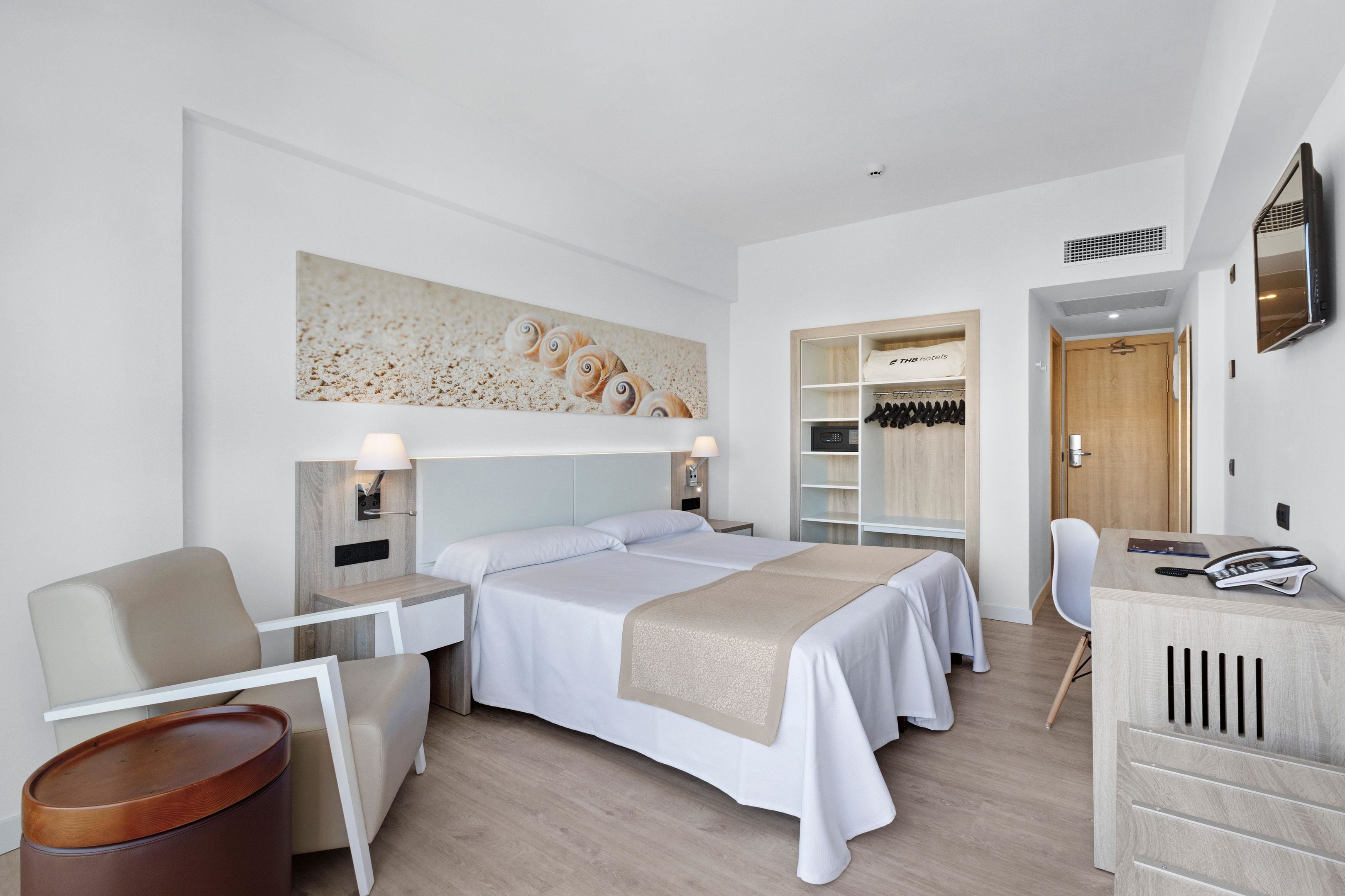 Habitación de hotel moderna con una cama grande, un escritorio, una silla y un armario.