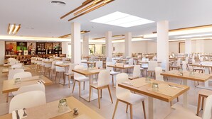 Ein großzügiger Essbereich mit mehreren Tischen und Stühlen, eine Bar mit verschiedenen Gegenständen und ein modernes Decken Design.