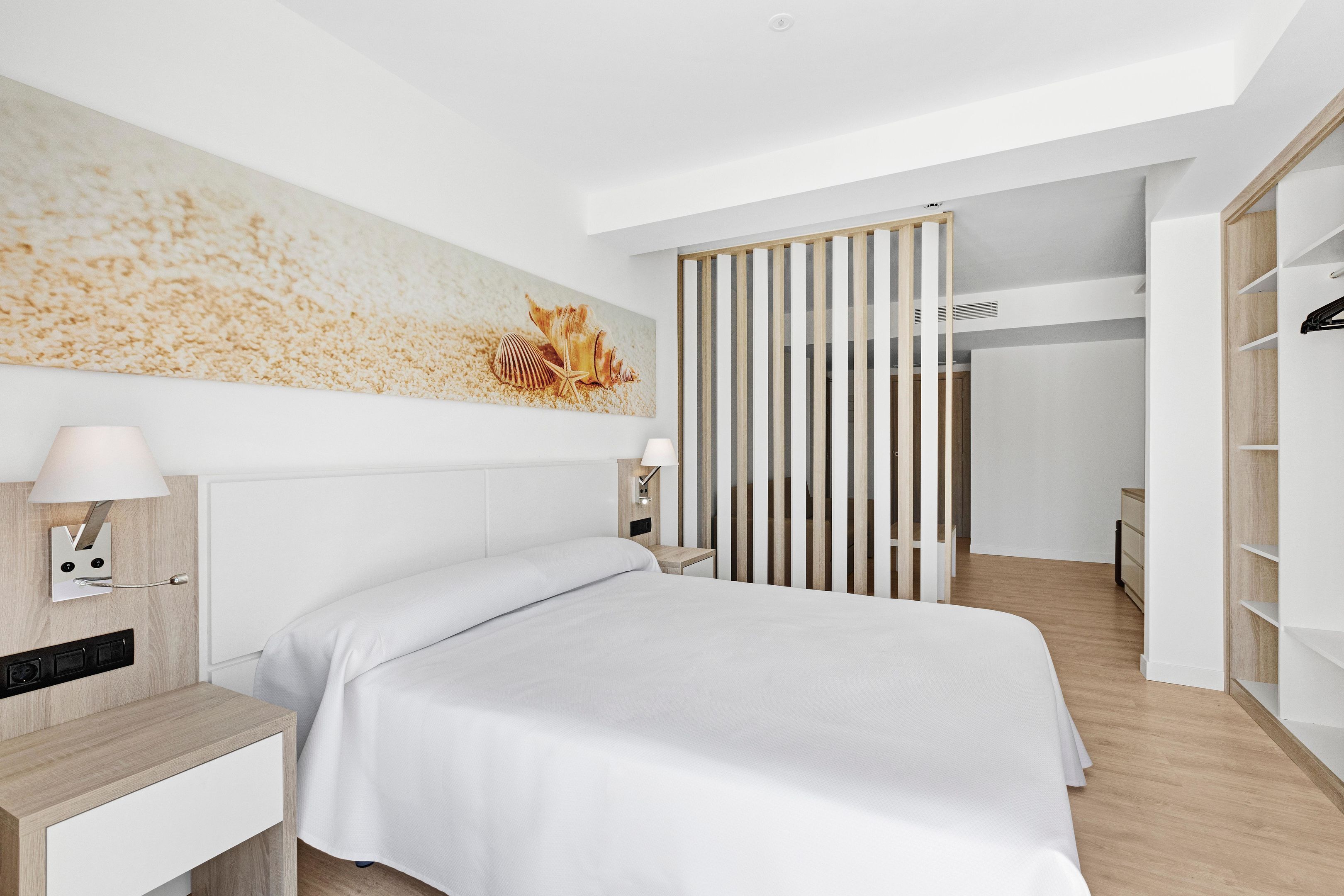 Ein modernes Schlafzimmer mit Bett, Nachttischen, einer Wandlampe und einem großen Kunstwerk.