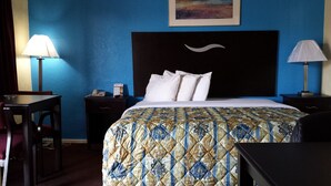 A hotel room with a bed, two bedside tables, a desk, and a chair. - American Inn Sedalia (Sedalia)