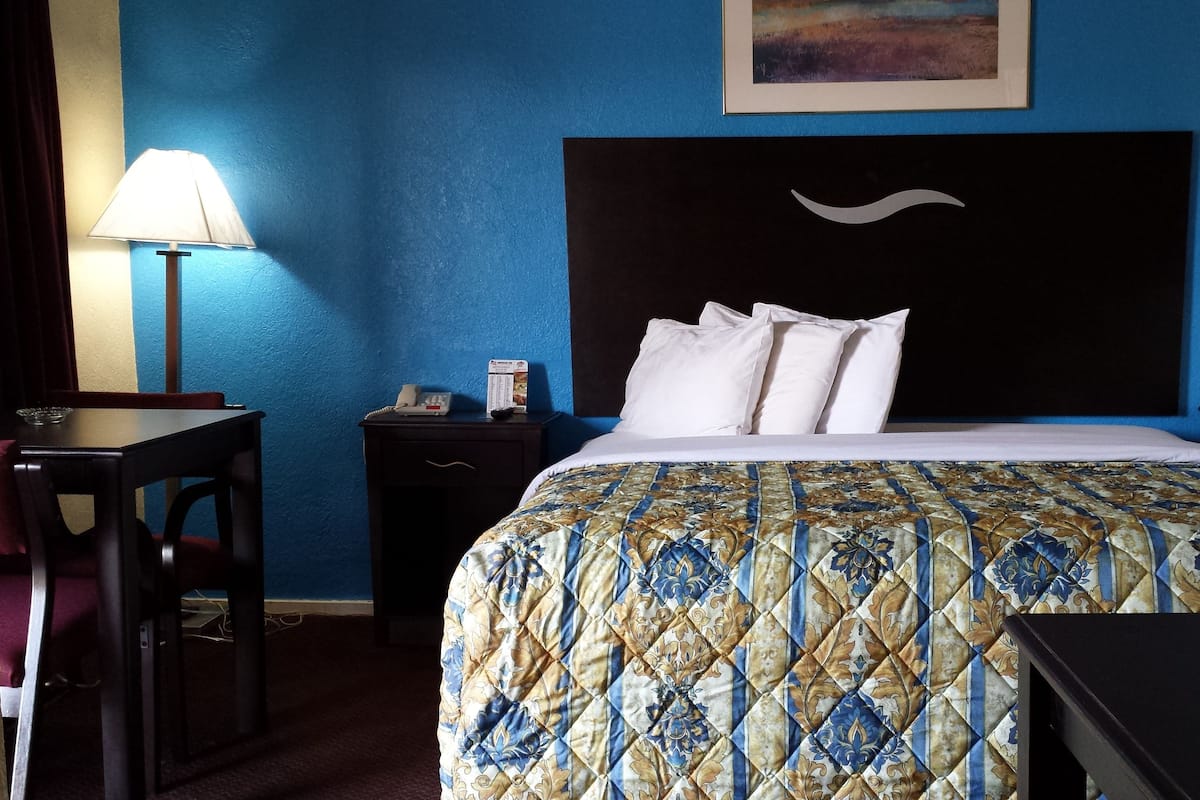 Una habitación de hotel con cama, dos mesitas de noche, un escritorio y una silla.