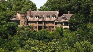 A large, rustic building surrounded by dense greenery. - American Inn Sedalia (Sedalia)