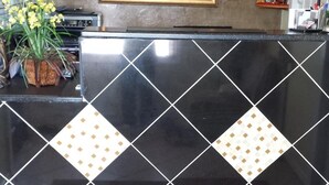 A reception desk with a black and white patterned tile design, a framed picture above it, and a colorful rug in front. - American Inn Sedalia (Sedalia)