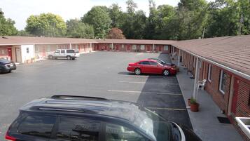 Un motel doté d’un parking, de plusieurs chambres et d’une voiture rouge garée sur le parking.