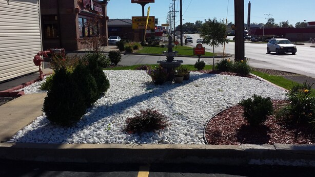 A landscaped area with white pebbles, shrubs, and a fountain. - American Inn Sedalia (Sedalia)