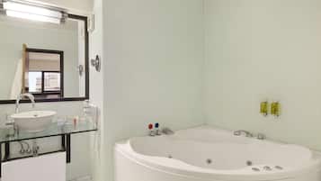 A modern bathroom with a glass-enclosed sink, a large freestanding bathtub, and a mirror above the sink.