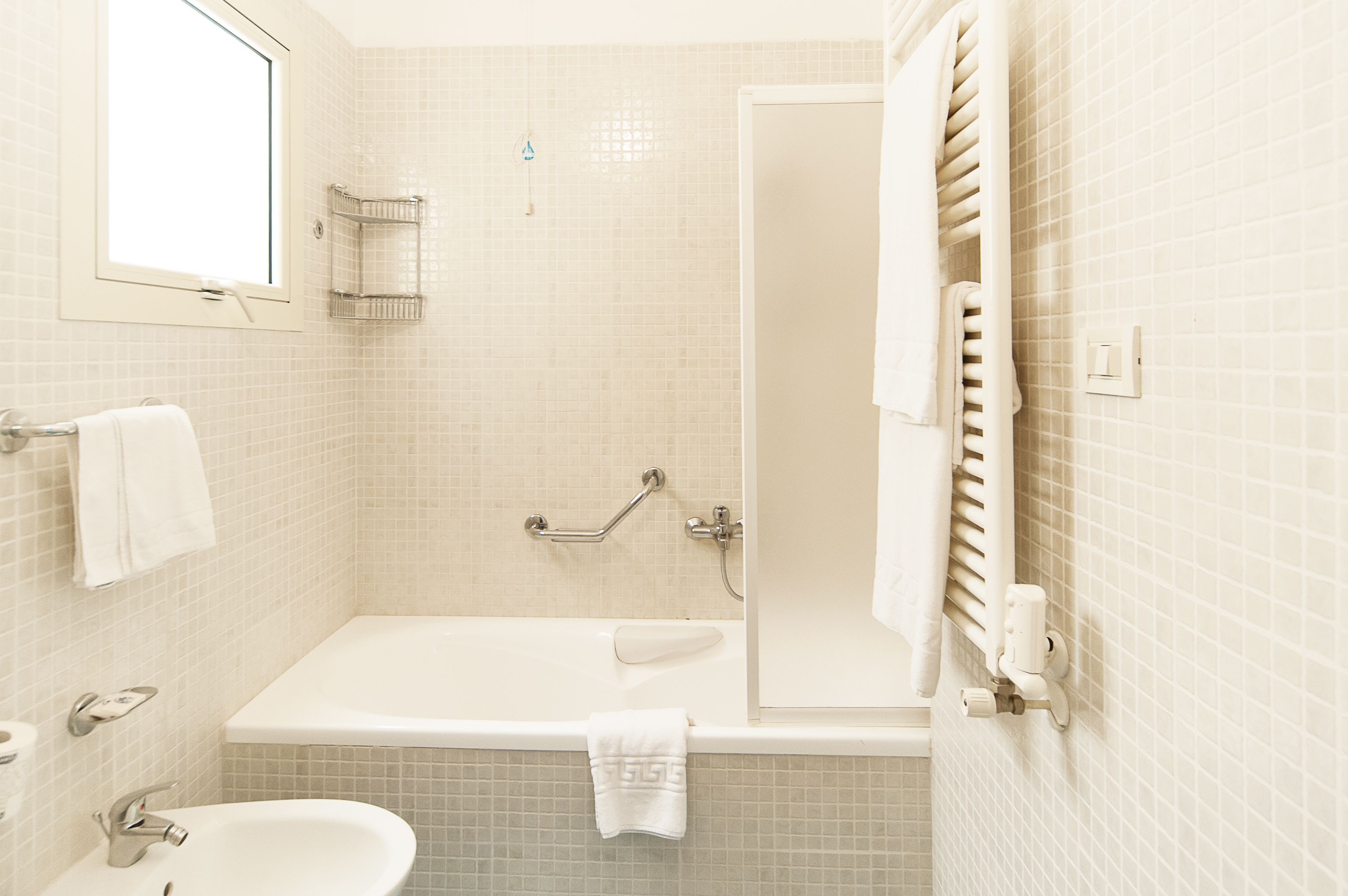 Un baño con bañera, lavamanos, inodoro y ventana.