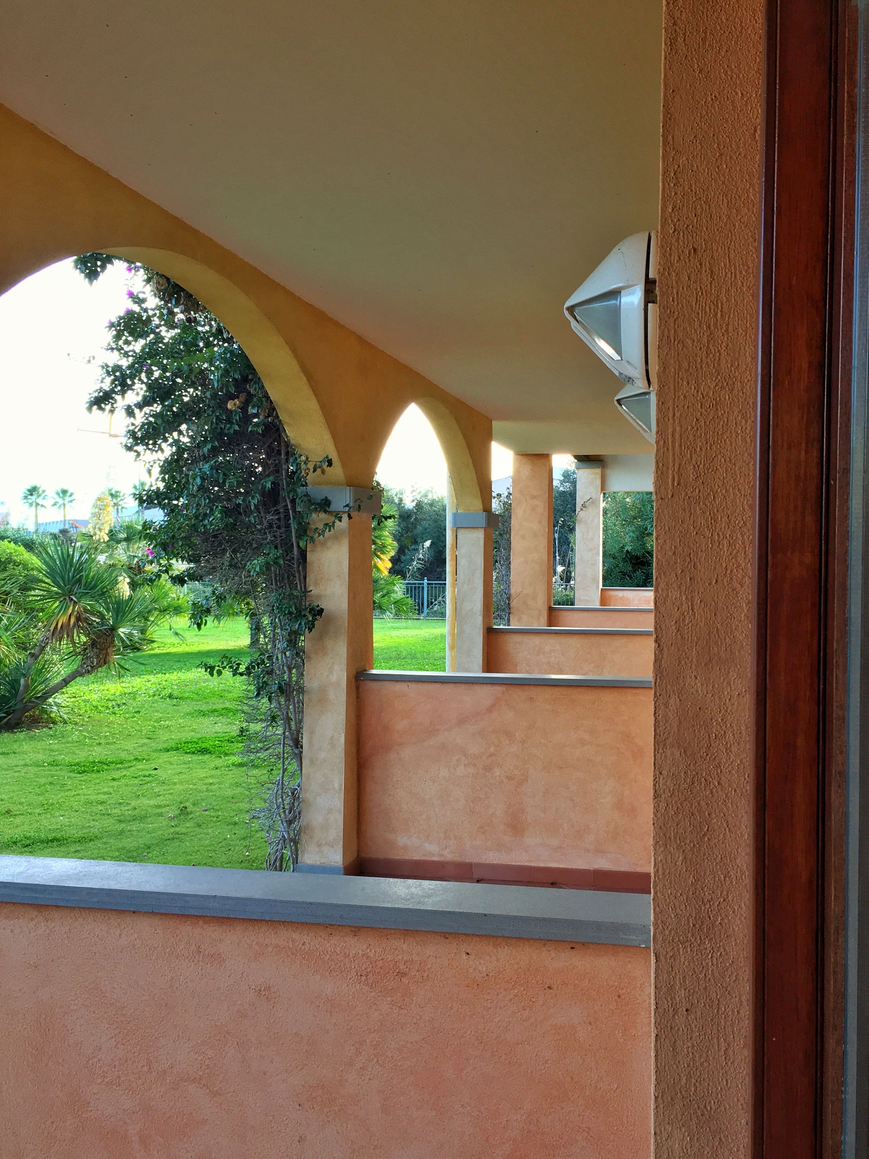 A covered outdoor area with a view of a green landscape.
