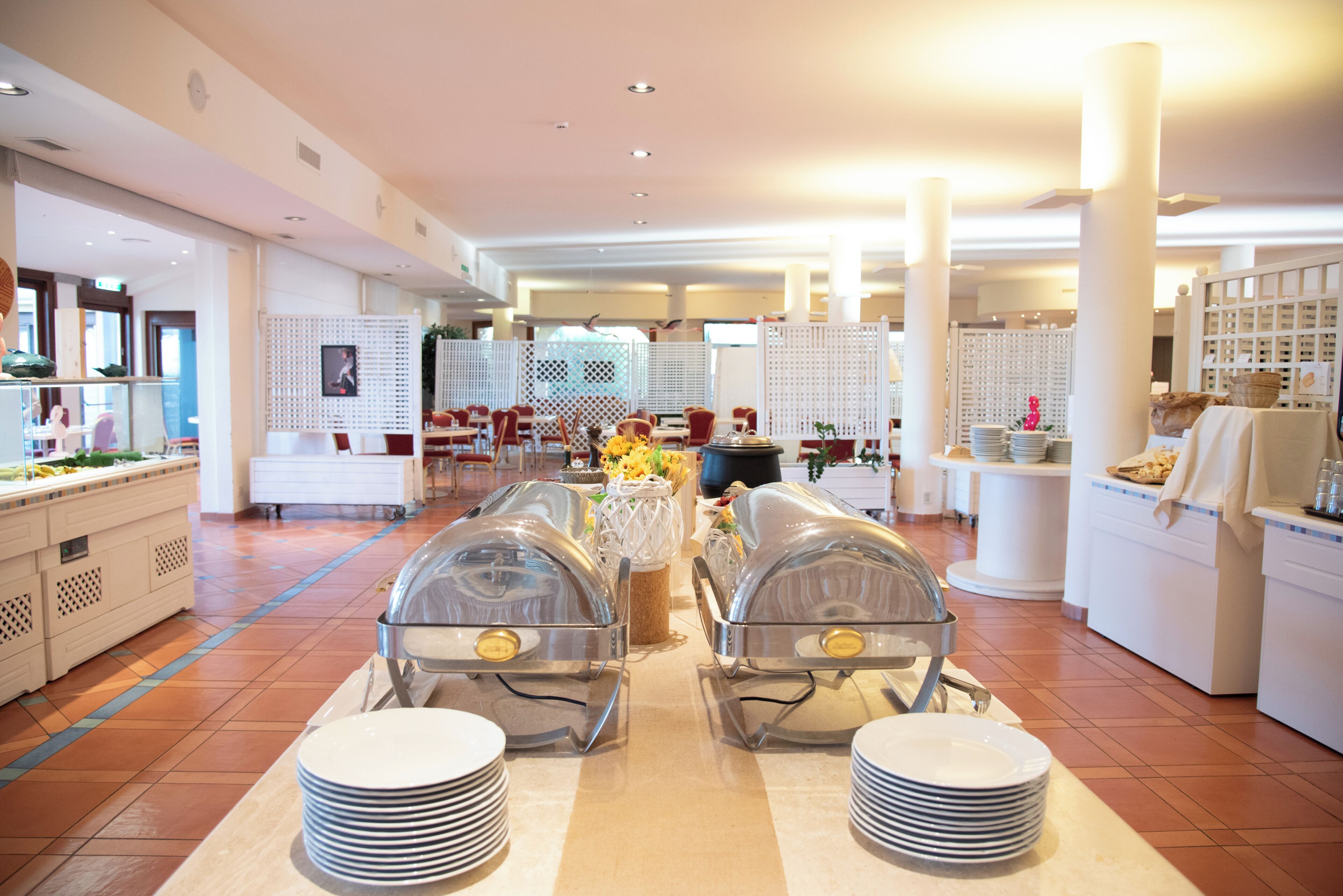 A buffet setup with glass-covered food displays, white buffet tables, and a tiled floor.