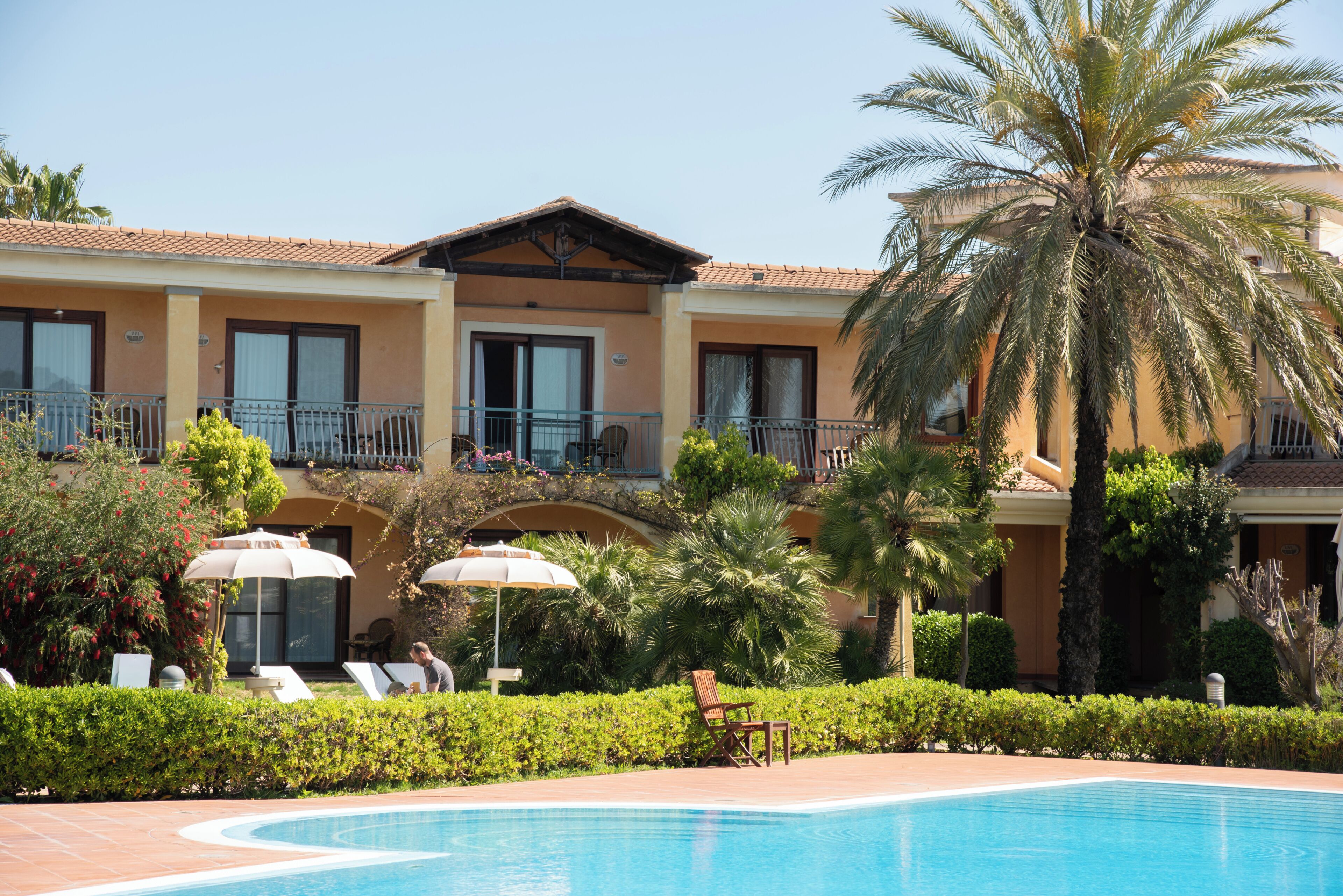 Un hôtel doté d’une piscine, de chaises longues et de palmiers.