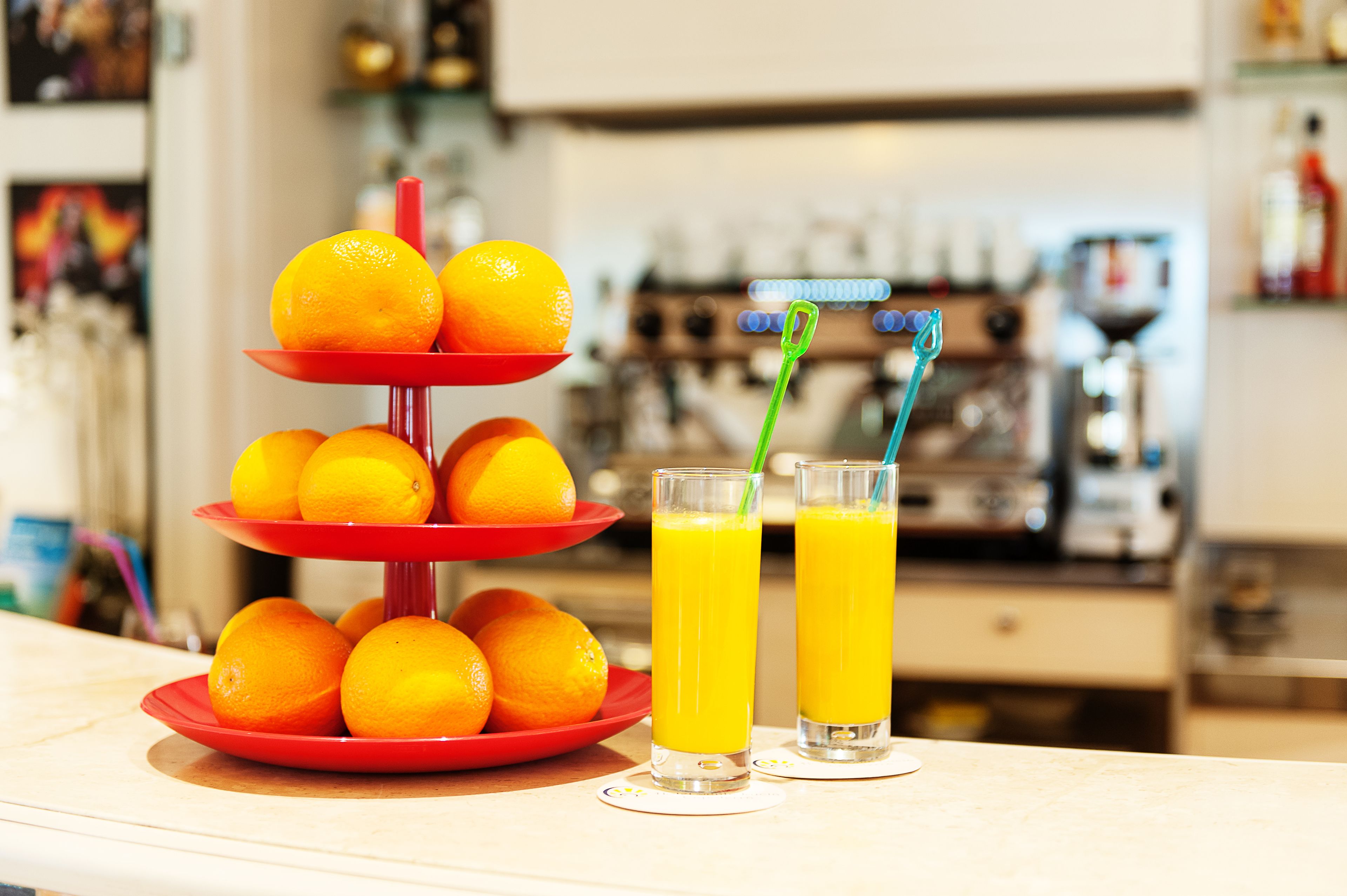 A three-tiered orange stand with oranges and two glasses of orange juice.