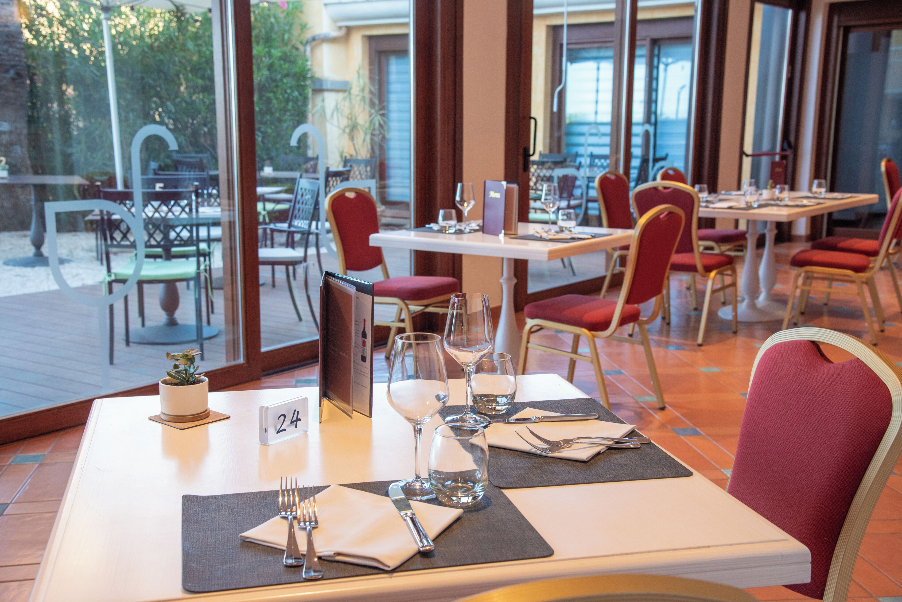 Ein Restaurant mit gedeckten Tischen, nummerierten Platzsets und Blick auf die Außenbereich-Terrasse.