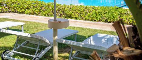 Un área junto a la piscina con sillones de descanso y una piscina.