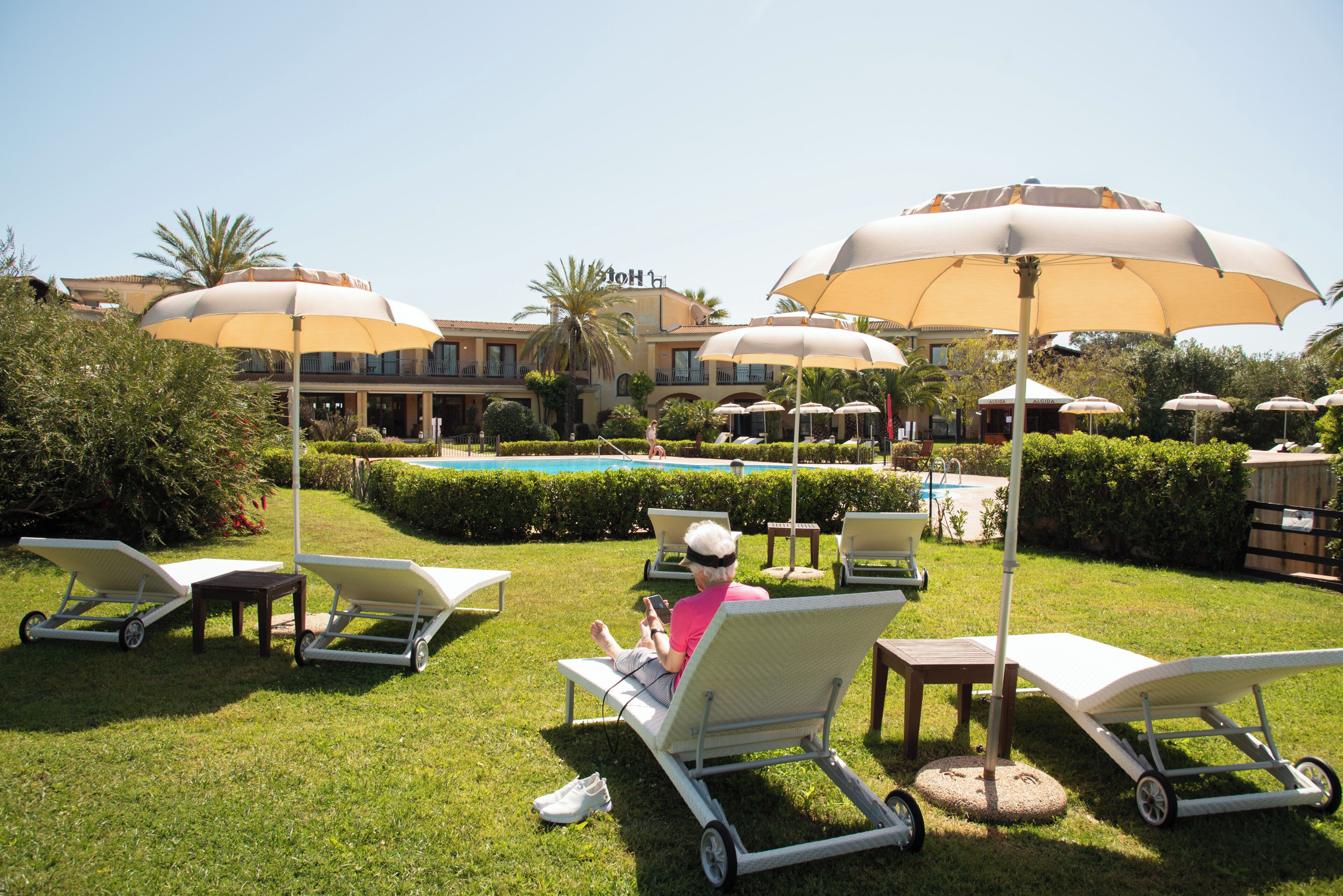 A poolside area with lounge chairs, umbrellas, and a pool.