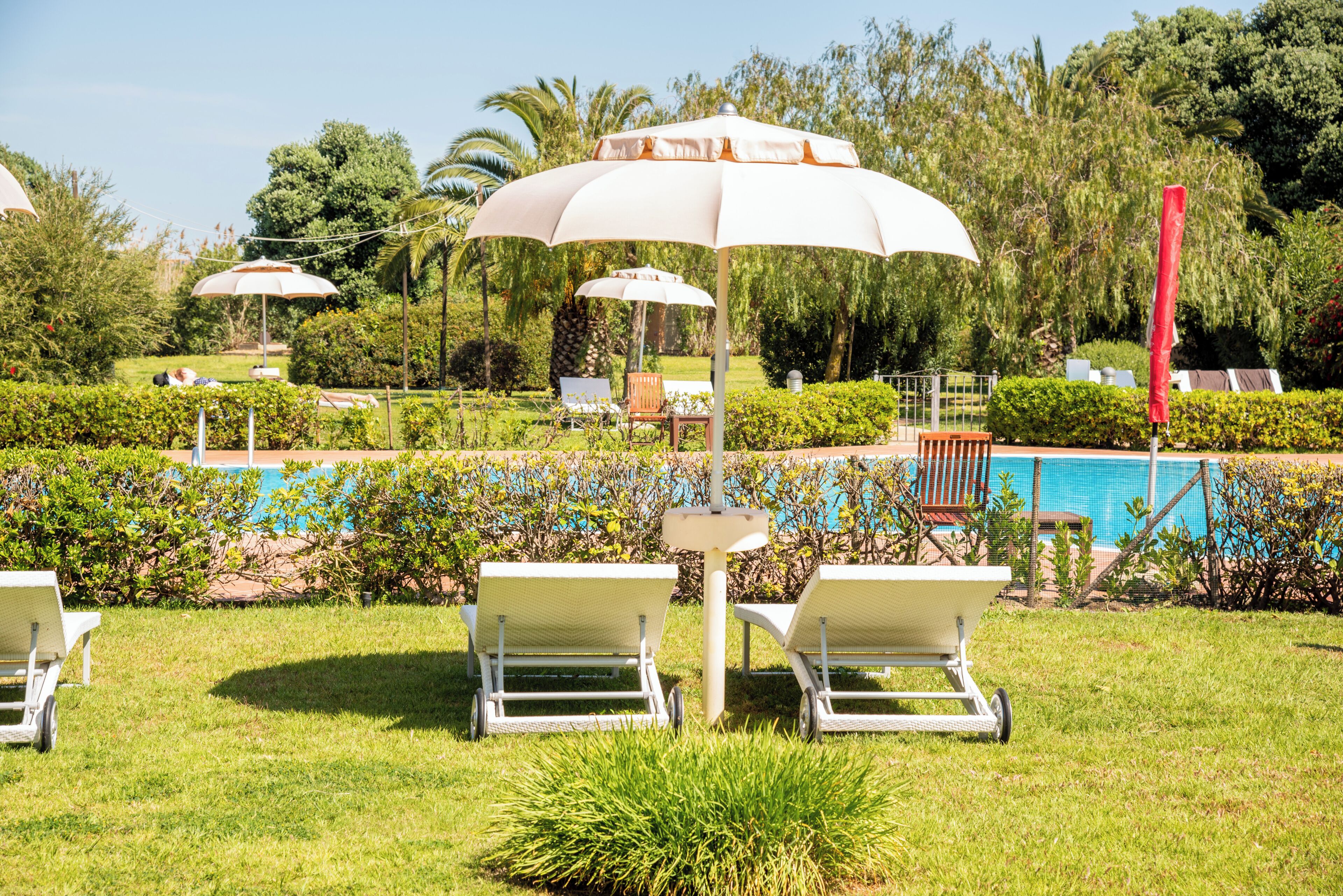 A poolside area with lounge chairs, umbrellas, and a clear view of the pool.