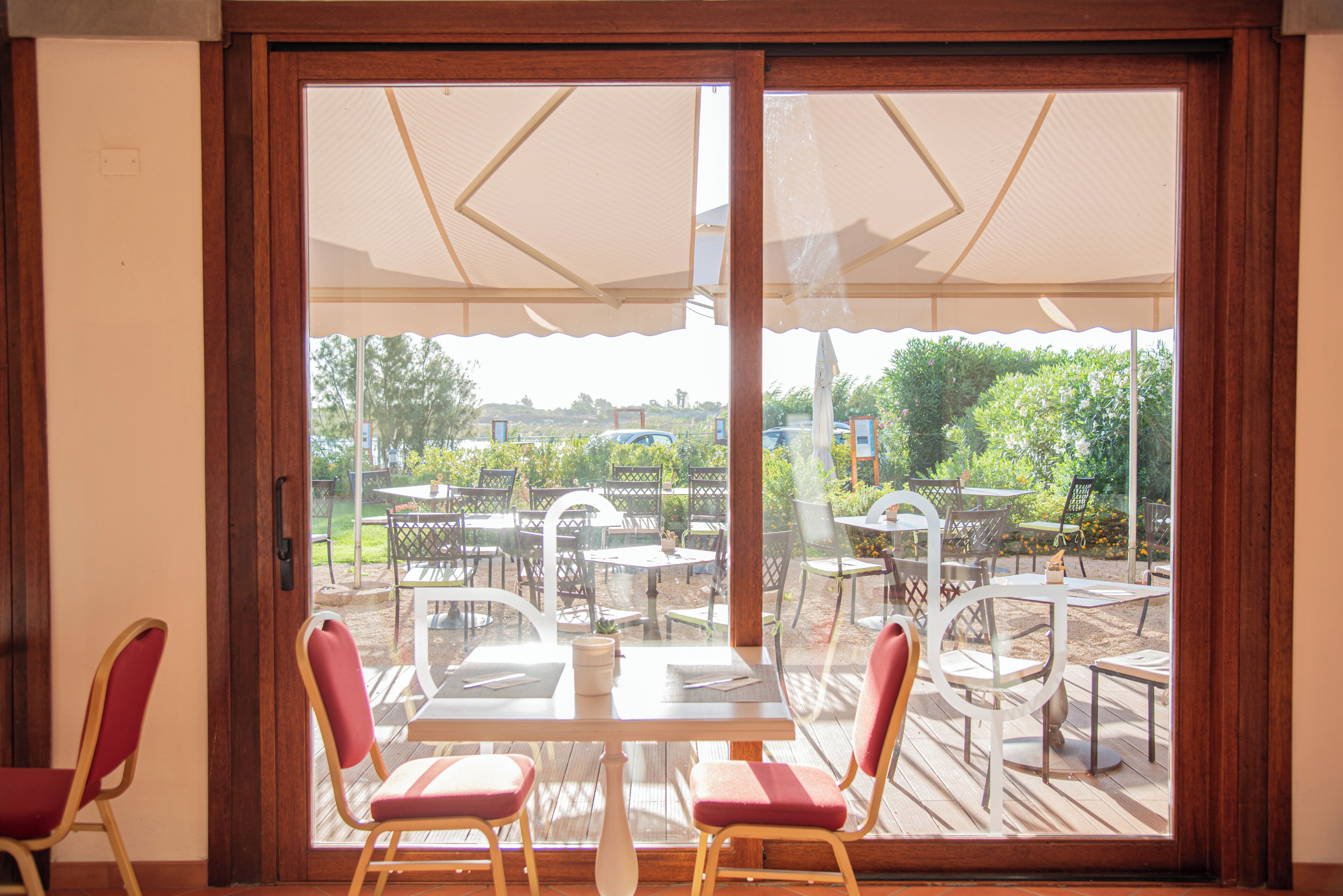 A room with a sliding glass door leading to an outdoor patio with tables and chairs.