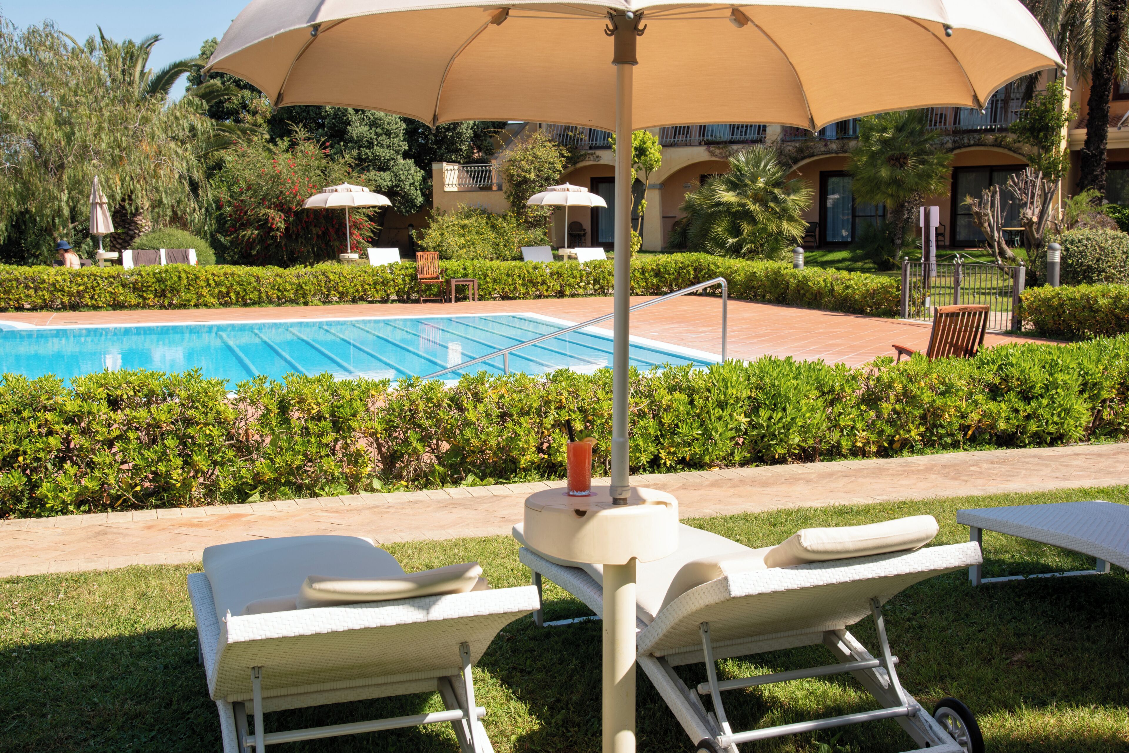 A pool area with lounge chairs, umbrellas, and a clear blue pool.