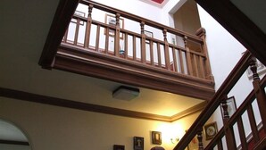 A multi-level interior with a wooden staircase, a skylight, and framed pictures on the walls. - The Glen Guesthouse (Selkirk)