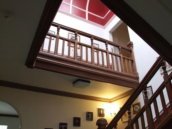 A multi-level interior with a wooden staircase, a skylight, and framed pictures on the walls.