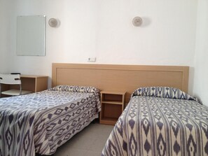 A room with two beds, a desk, and a chair.