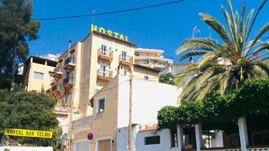 Een meerlaags gebouw met balkons en een bord waarop 'HOSTAL SAN TELMO' staat.