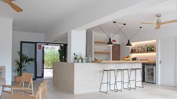 A modern kitchen with a central island, bar stools, pendant lighting, and a refrigerator.