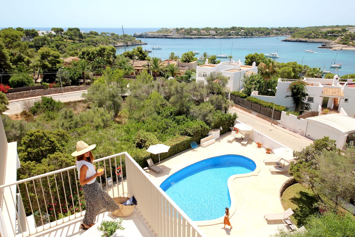 A residential area with a swimming pool, a balcony with a railing, and a view of the sea with boats.