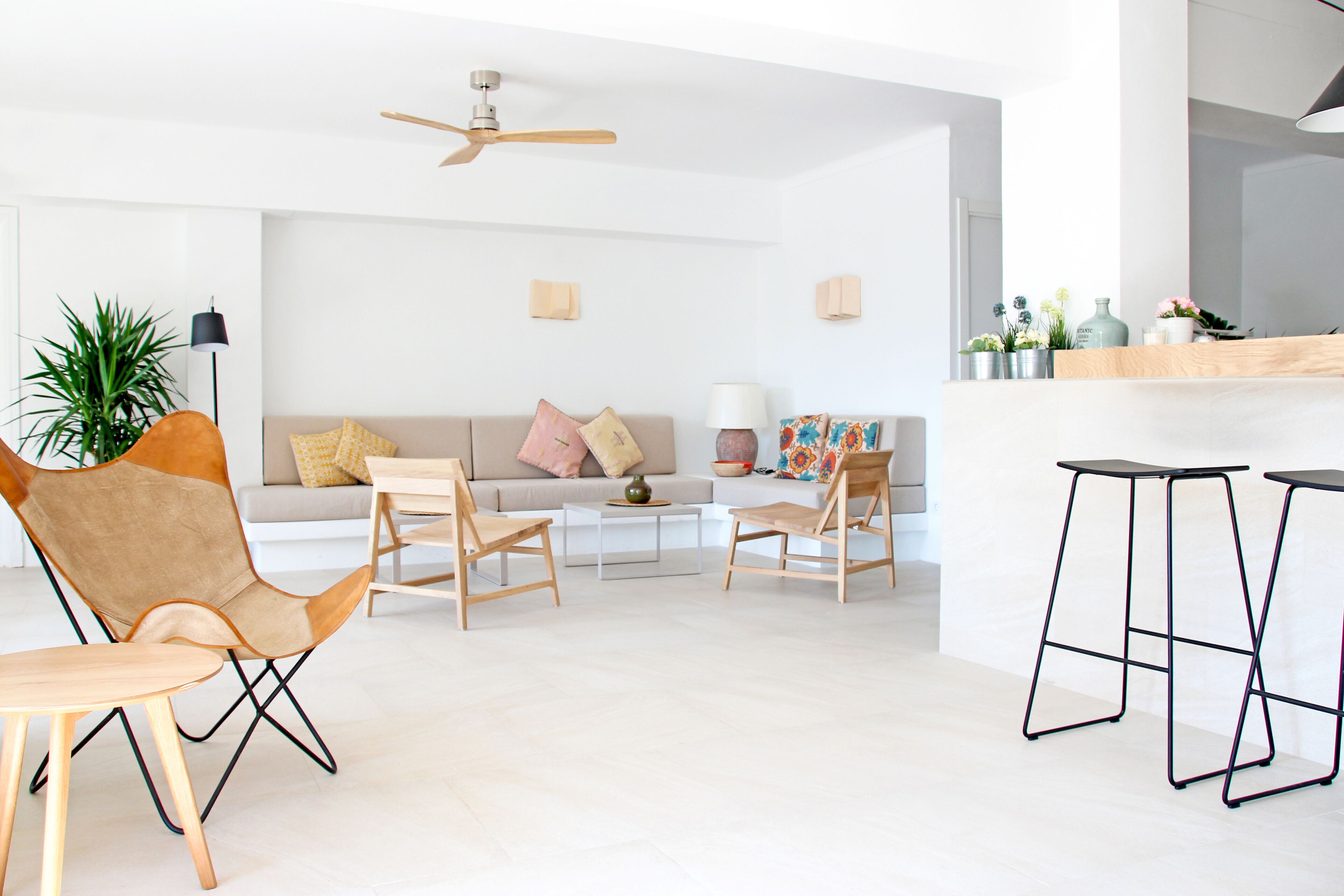 Una sala de estar moderna con un sofá, dos sillones, una mesa de centro y una zona de bar con taburetes.