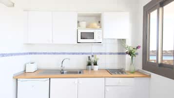 A compact kitchen with white cabinets, a microwave, a toaster, and a window with a view.