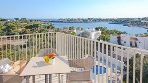 A balcony with a table and chairs overlooking a coastal view. - Aparthotel Niu d´Aus (Santanyi)