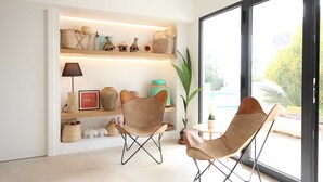 A modern living room with two leather chairs, a small table, and a shelf with decorative items. - Aparthotel Niu d´Aus (Santanyi)