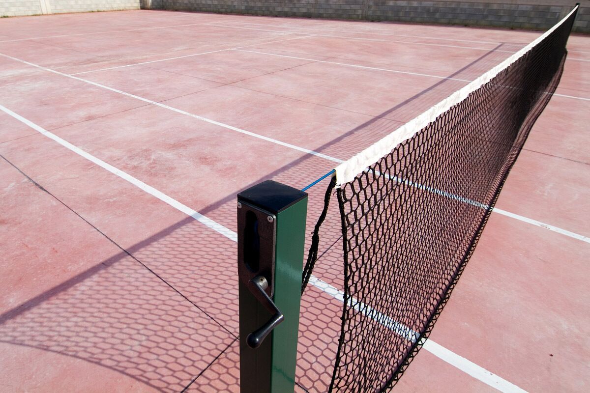 A tennis court with a net and a metal post.